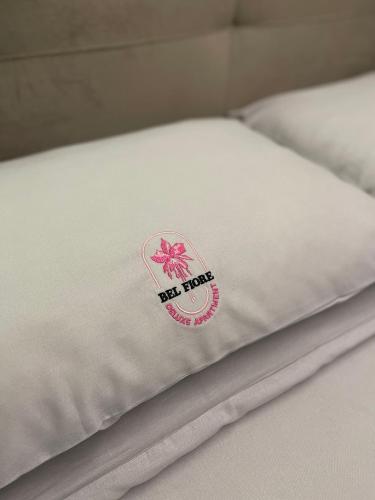 a close up of a white bedsheet with a pink flower on it at Bel Fiore Deluxe Apartment in Genova