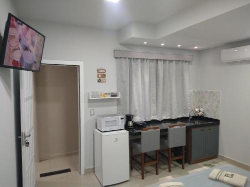 a small kitchen with a table and a microwave at Cantinho da Vila Hospedagem in Penha