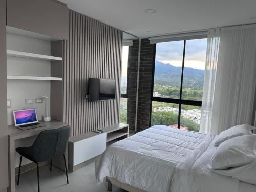a bedroom with a bed and a desk with a computer at Luxury Studio con Vista in Cali