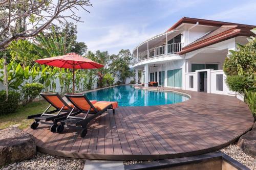 eine Terrasse mit 2 Stühlen und einem Sonnenschirm neben einem Pool in der Unterkunft Villa Sirion in Kamala Beach