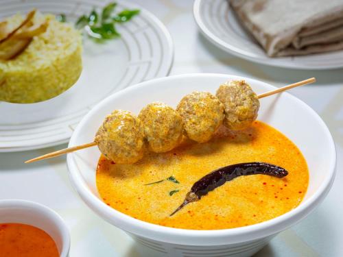 a bowl of soup with meatballs on top of it at Radisson Bengaluru City Center in Bengaluru