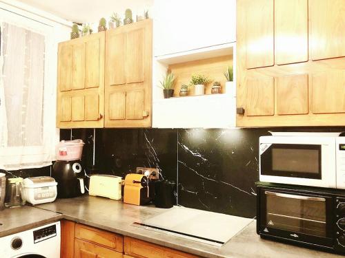 a kitchen with wooden cabinets and a microwave at Big apartment 10 minuits from Notre Dame de Paris in Choisy-le-Roi