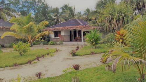 a house in the middle of a field with palm trees at Residence Monique in Ile aux Nattes