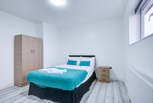 a bedroom with a bed with blue sheets and blue pillows at CrossVille Homes - Double rooms in Navestock