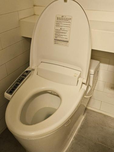 a white toilet with the lid up in a bathroom at Urban Space Sinnonhyeon in Seoul