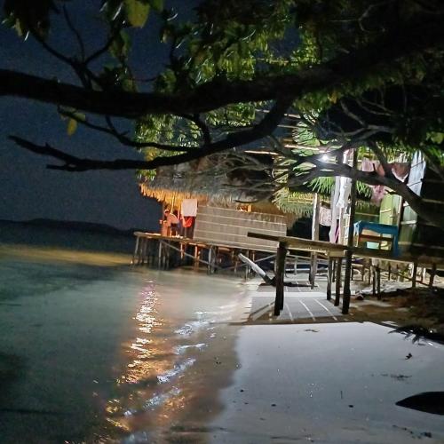 a park bench sitting on the beach at night at Coco Huts Guest House in Waisai
