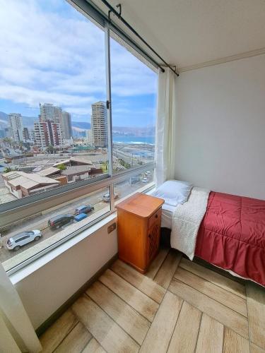 a bedroom with a large window with a view of a city at Naulitus Departamentos Vista Panorámica frente al Mar in Iquique