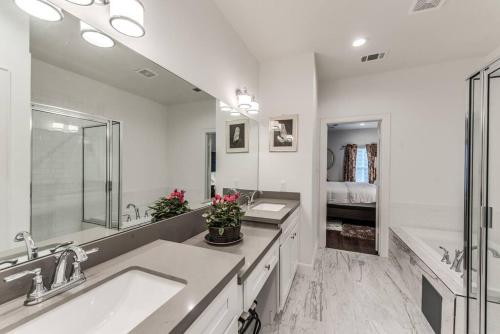 a white bathroom with two sinks and a large mirror at Stylish 3 BDR House 5 miles to Downtown! in Houston