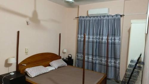 a bedroom with a wooden bed and a curtain at Luxury House in Porto-Novo