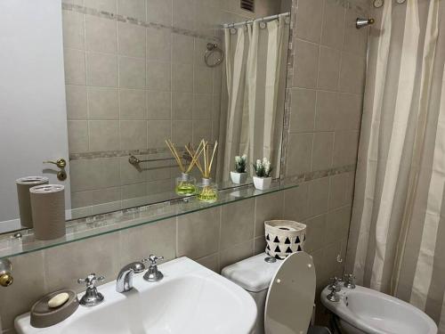 a bathroom with a sink and a toilet and a mirror at En el Corazón de la Quinta. in Villa Marini