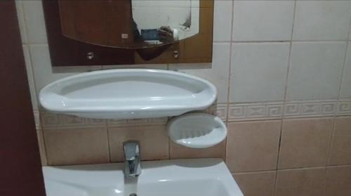 uma casa de banho com um lavatório branco e um espelho. em Partion Room Rental em Sharjah
