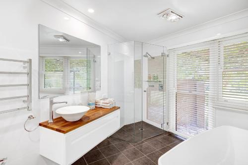 a white bathroom with a sink and a tub at Birches Mudgee in Mudgee