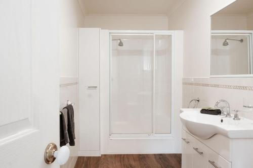 a white bathroom with a shower and a sink at Port Fairy Holiday Park in Port Fairy
