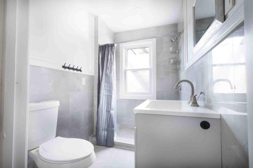 a white bathroom with a toilet and a sink at Elegant 1BR 1 Bath apartment minutes the falls in Niagara Falls