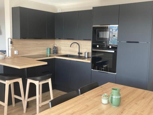 eine Küche mit schwarzen Schränken und einem Holztisch in der Unterkunft Appartement de charme 4 pièces, 8 pers, balcon, proche pistes et centre, Vallandry - FR-1-411-875 in Landry