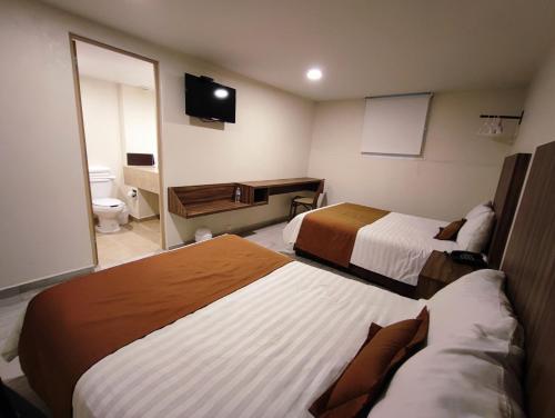 a hotel room with two beds and a television at Hotel Plaza Morelos in Toluca