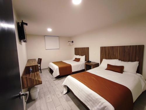 a hotel room with two beds and a tv at Hotel Plaza Morelos in Toluca