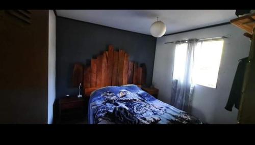 ein Schlafzimmer mit einem Bett mit einer blauen Decke und einem Fenster in der Unterkunft Cabañas chivo siete tazas in El Torreón