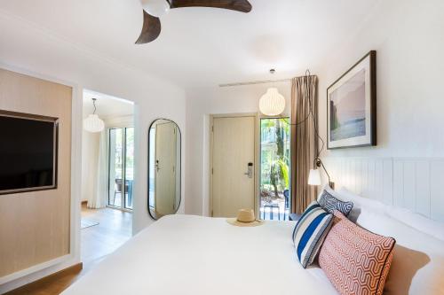 a bedroom with a large white bed and a tv at Mantra Club Croc in Airlie Beach