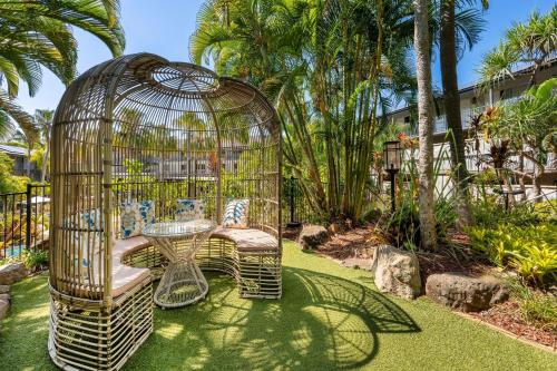 a bird cage with two chairs and a table in it at Mantra Club Croc in Airlie Beach