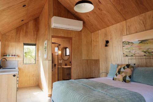 Bicheno Garden Cottages في بيتشينو: غرفة نوم بجدران خشبية وسرير في غرفة