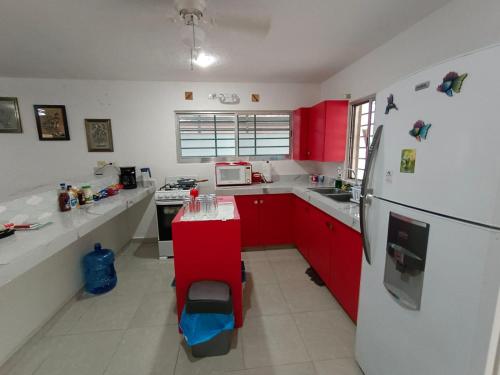uma cozinha com armários vermelhos e um frigorífico branco em Casa colibri. em Progreso