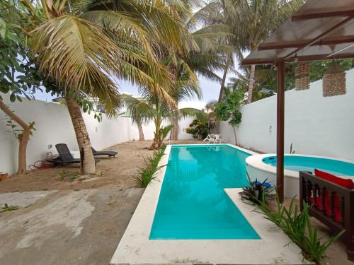 uma piscina no quintal de uma casa com palmeiras em Casa colibri. em Progreso
