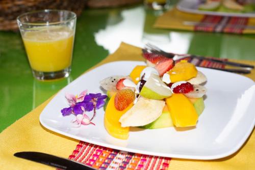Kairí Lodge Natural Reserve في مانيزاليس: صحن فاكهة على طاولة مع كوب من عصير البرتقال