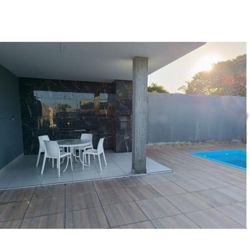 eine Terrasse mit Tisch und Stühlen neben einem Pool in der Unterkunft Casa com piscina em Guarajuba 4quartos in Camassari
