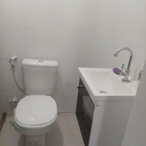 ein Badezimmer mit einer weißen Toilette und einem Waschbecken in der Unterkunft Casa com piscina em Guarajuba 4quartos in Camassari