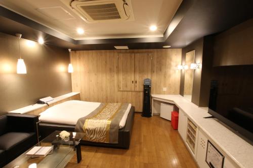 a hotel room with a bed and a couch at K-WAVE in Kasukabe