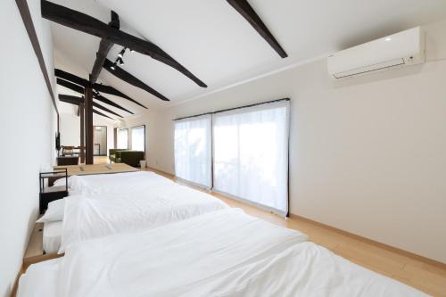 a bedroom with three beds and a large window at 丘の上から海が見える一棟貸しヴィラ しまいろ長手 