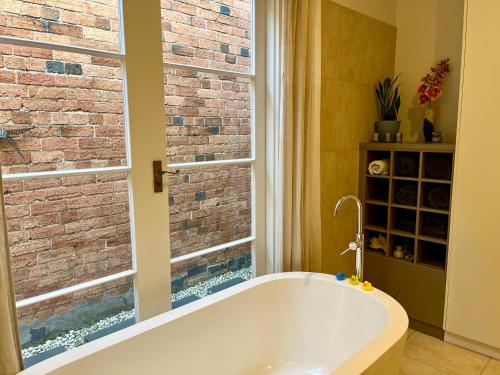 a bath tub in a bathroom with a brick wall at Lovely Victorian Terrace - Entire home in Melbourne