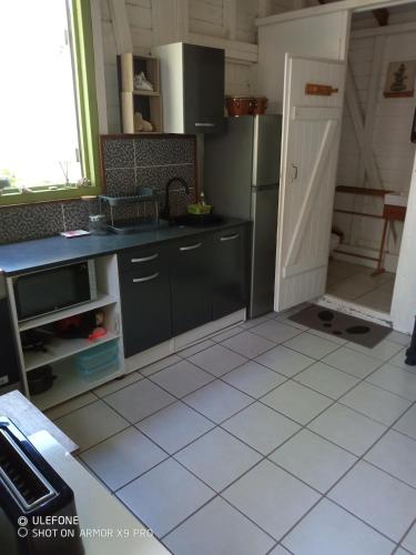 a kitchen with a refrigerator and a tiled floor at Le Bungalow des Hauts de la Prairie in Le François