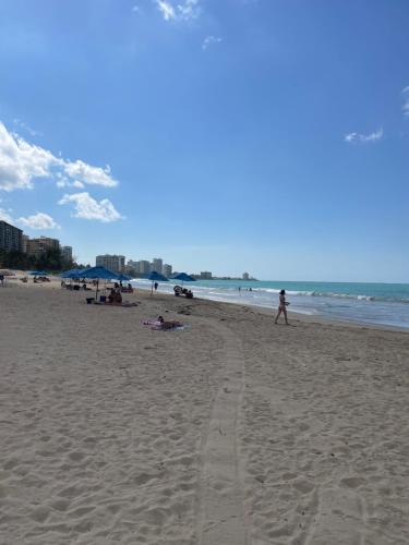 a group of people walking on the beach at Beach Front Condo in Isla Verde! in San Juan