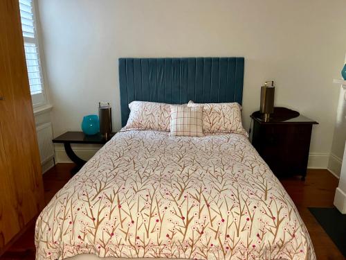 a bedroom with a large bed with a blue headboard at Lovely Victorian Terrace - Entire home in Melbourne