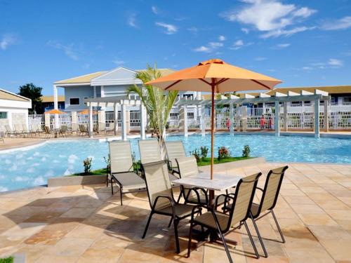 a table and chairs with an umbrella next to a pool at LACQUA Di'Roma, park 24h, cozinha com fogão, 5 pessoas gG in Caldas Novas