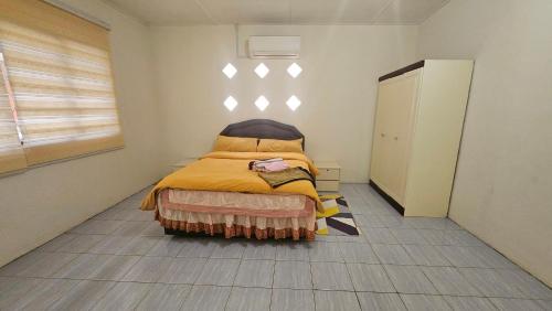 ein kleines Schlafzimmer mit einem Bett mit einer gelben Decke in der Unterkunft Syafeqah Homestay Kimanis Papar in Kimanis