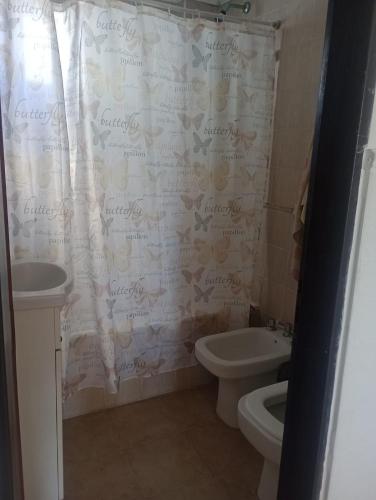 een badkamer met een toilet, een wastafel en een douchegordijn bij DEPARTAMENTO EN LA PERLA in Mar del Plata
