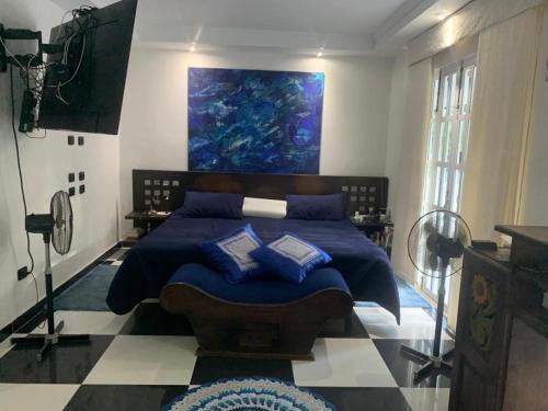 Un dormitorio con una cama azul con una pintura en la pared en Quinta El Diamante, en Villavicencio