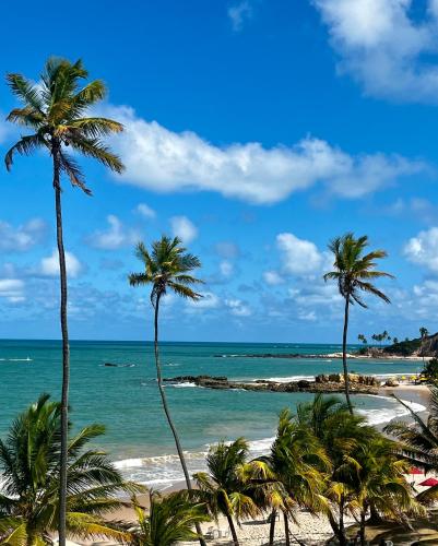 a beach with palm trees and the ocean at Brisas de Tabatinga Flat in Conde