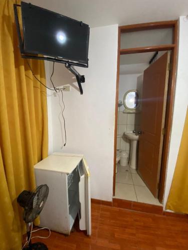 Habitación con TV en la pared y aseo. en Hostal Pacasmayo Beach, en Pacasmayo
