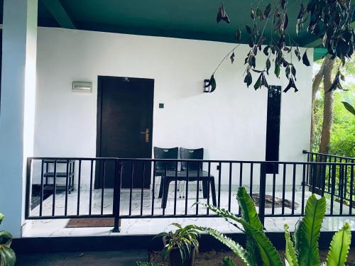 2 chaises assises sur la terrasse couverte avant d'une maison dans l'établissement Green House Resort, à Sigirîya