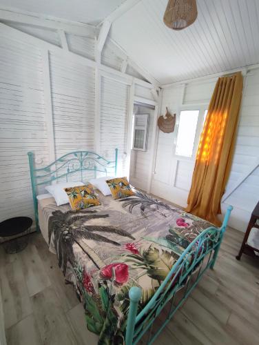 a bedroom with a blue bed with flowers on it at Bungalow Soleil Levant in Le Robert