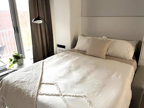 ein weißes Bett in einem Zimmer mit Fenster in der Unterkunft App en Plein Centre de Montréal - Quartier des Spectacles in Montreal