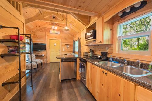 Eden Cabin Forested Tiny Home On Lookout Mtn في تشاتانوغا: مطبخ بدولاب خشبي ومغسلة في كابينة