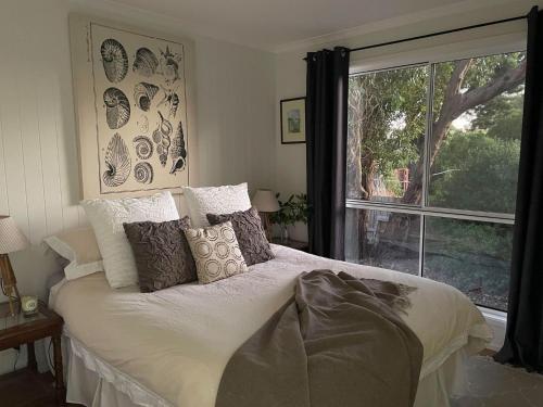 a bedroom with a bed and a large window at Bangalla Inlet Side in Inverloch