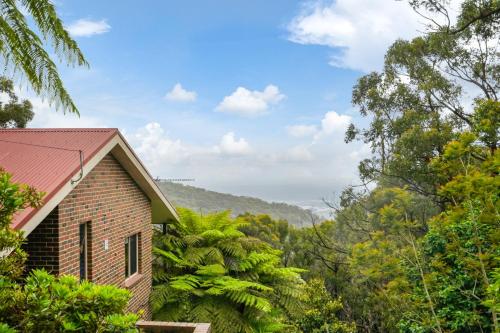 a brick house with a red roof in the forest at Embrace Nature's Beauty in Ferny Creek in Ferny Creek