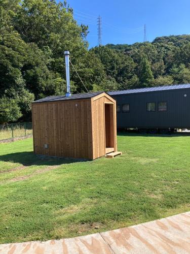a small wooden shed in a field of grass at Luxury Trailers 離宮 伊勢 in Sōchi