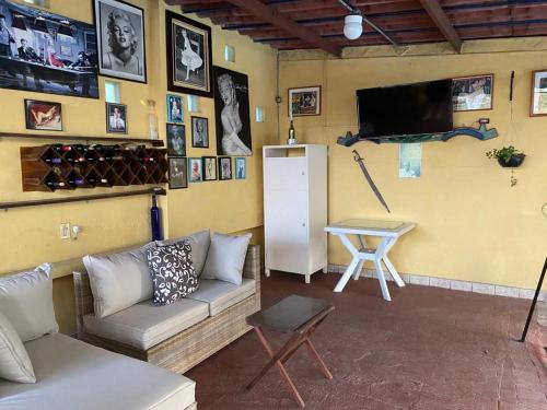 ein Wohnzimmer mit einem Sofa, einem TV und einem Tisch in der Unterkunft Quinta Ángeles in Cuernavaca